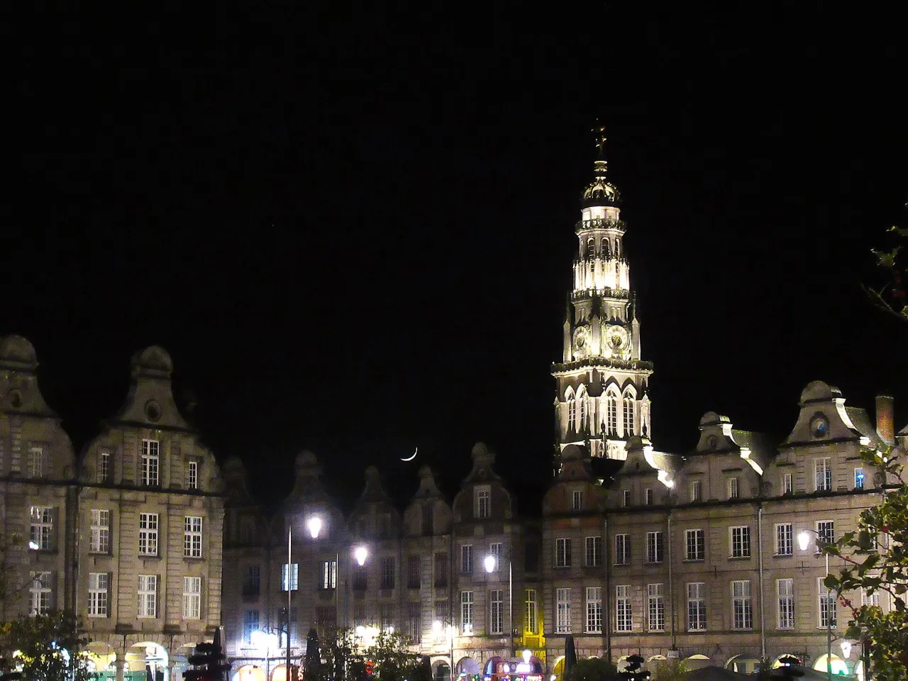 Le beffroi d’Arras illuminé la nuit au-dessus des façades des Places